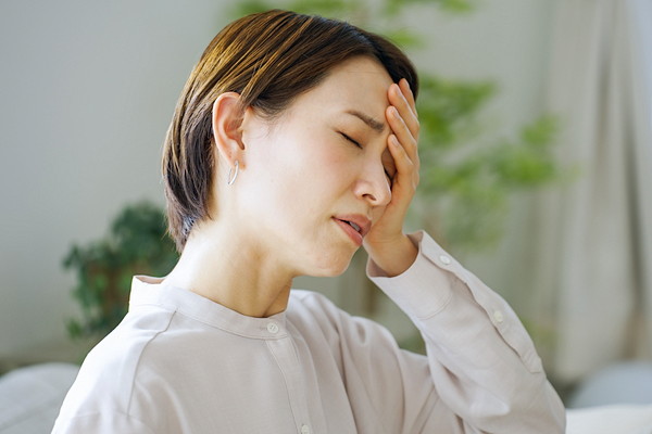 体調不良で頭を抱える女性